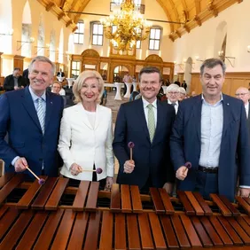 Vier Menschen mit Schlegeln in der Hand vor einem Marimbaphon (Holzinstrument): Christian Wulff (Bundespräsident a. D. und Präsident des Deutschen Chorverbands) neben Prof. Dr. Julia Lehner (2. Bürgermeisterin Stadt Nürnberg), Marcus König (Oberbürgermeister der Stadt Nürnberg), Dr. Markus Söder (Ministerpräsident des Freistaates Bayern) 